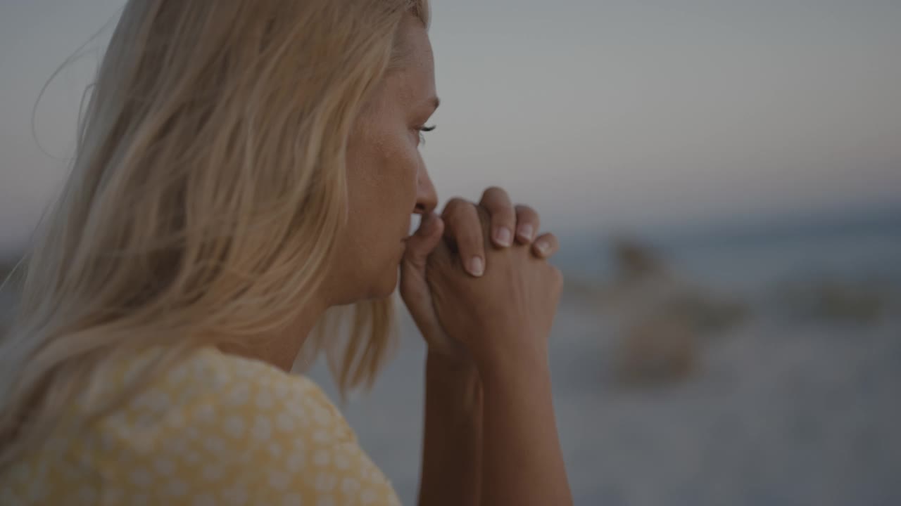 一个深思熟虑的女人坐在沙滩上的慢动作视图，撒丁岛。视频素材