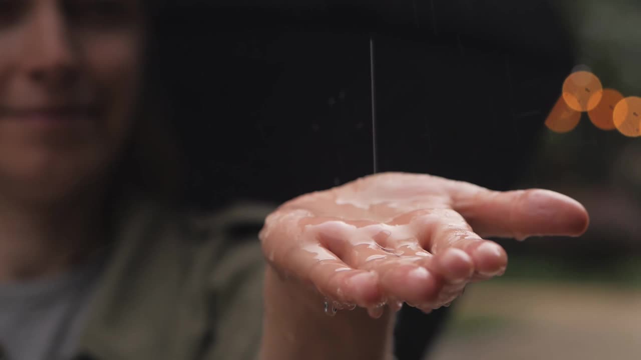 雨水落在一个打着伞的女人的手掌上视频素材