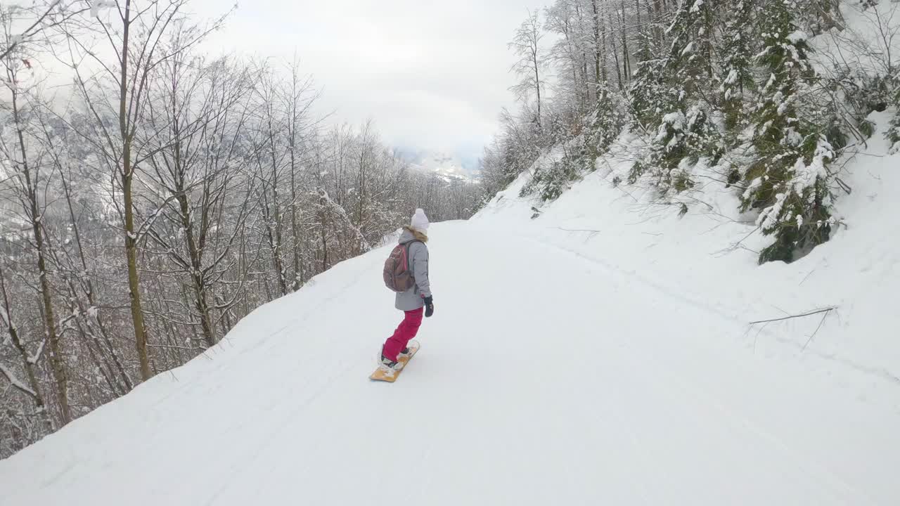 一个陌生的女人沿着滑雪胜地的斜坡滑过一片森林。视频素材