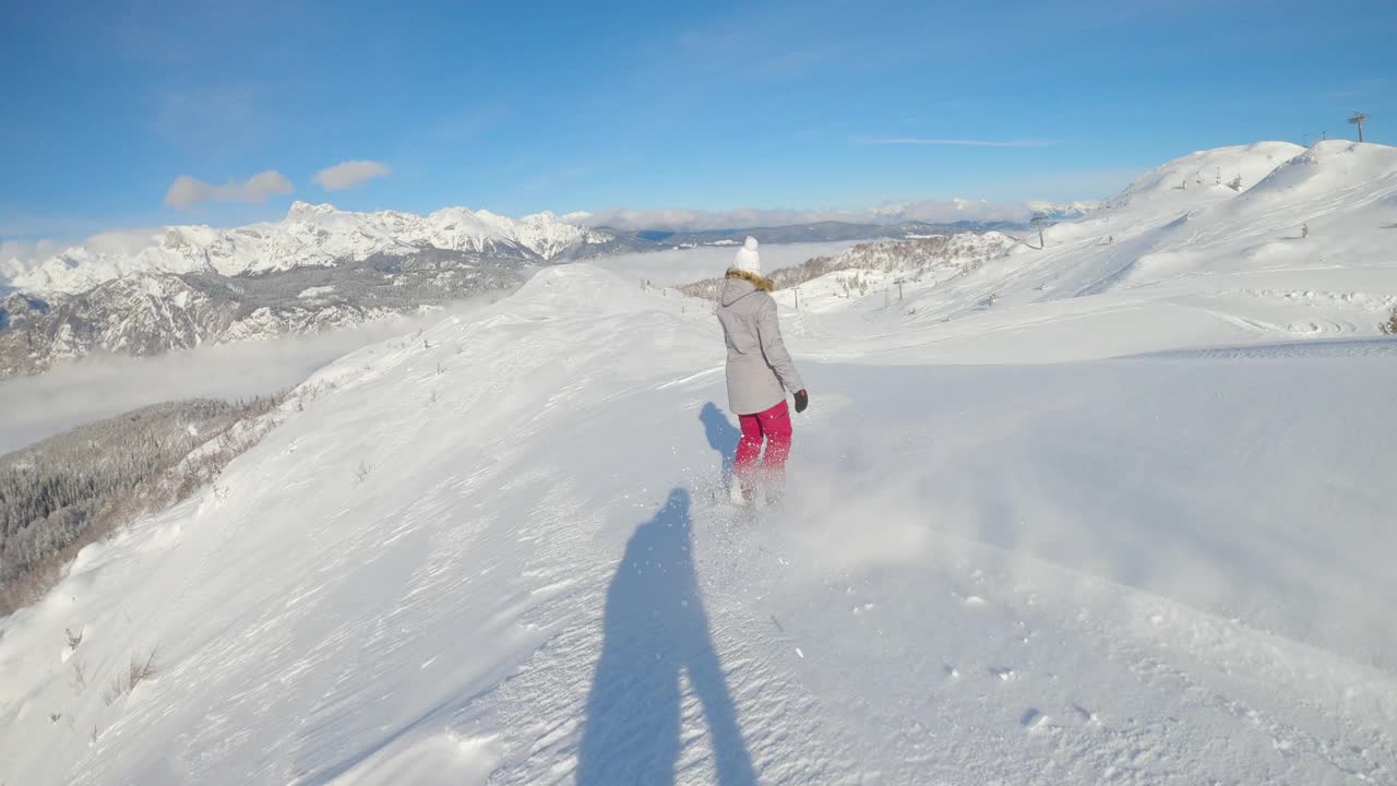 慢动作:女子单板滑雪运动员在滑出雪道时，将刚刚撒下的雪撕碎。视频素材