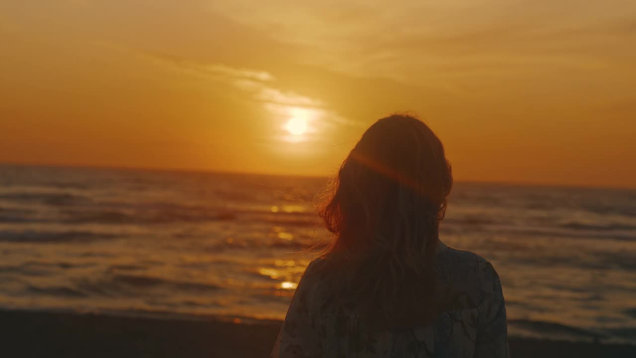 一个深思熟虑的女人看着日落的慢镜头。视频素材