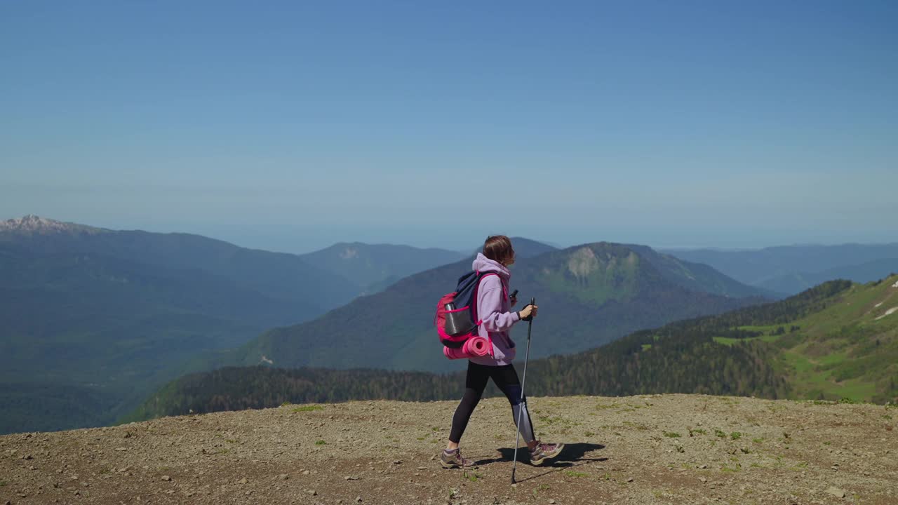 徒步登山，背着背包的女游客正在山顶上行走视频素材