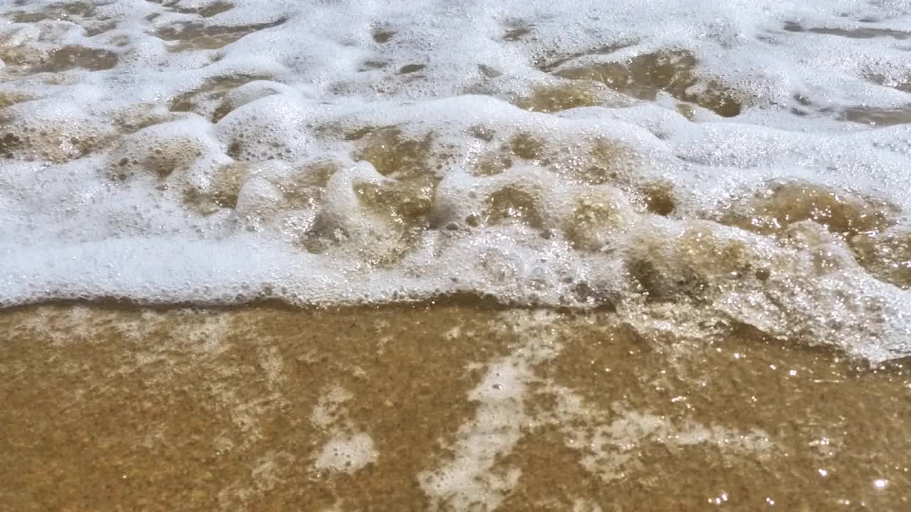 海浪卷上白色沙滩的特写镜头视频素材