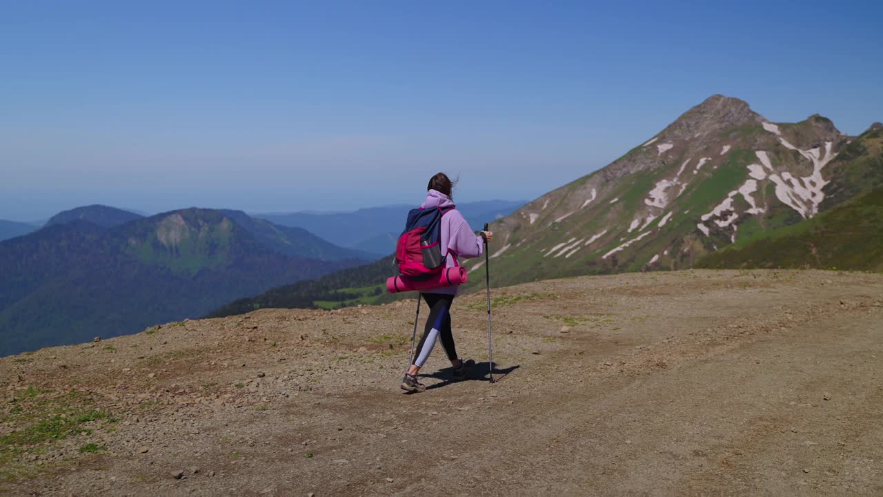 在山区徒步旅行，年轻的女游客是步行和背着背包，独自旅行视频素材