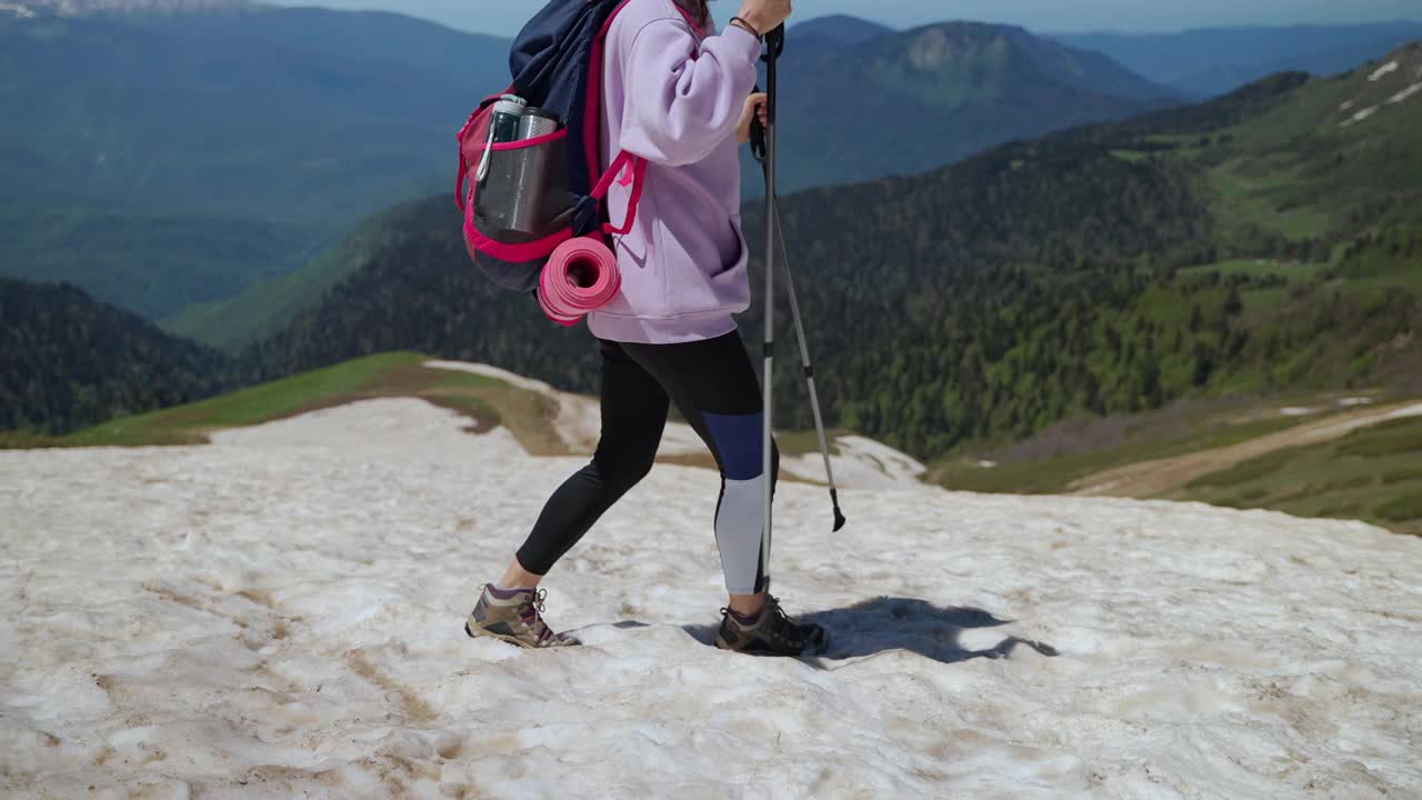 徒步旅行者在山顶的雪地上行走，拿着登山杖的女人在旅行和探索视频素材