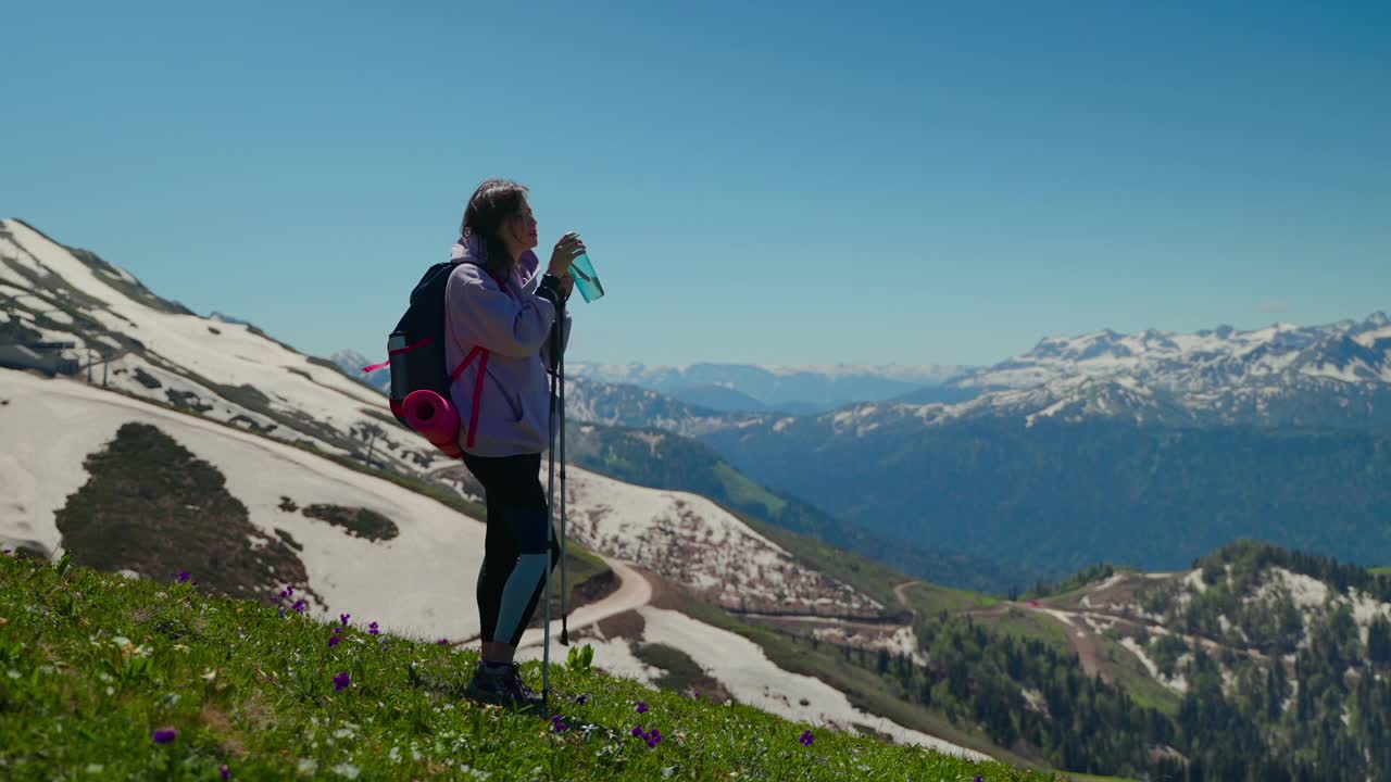 女背包客在山顶喝水，疲惫的徒步旅行者在休息视频素材