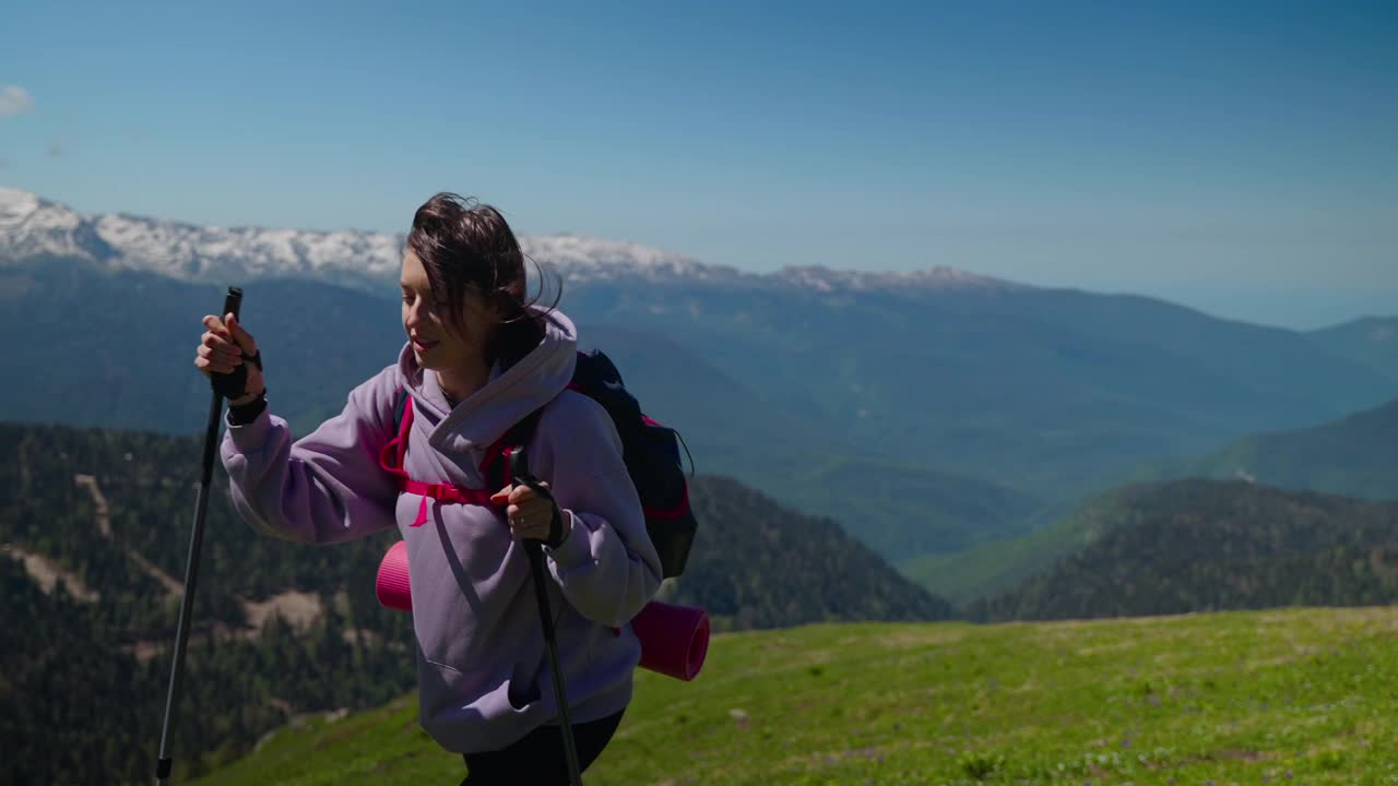 在山上旅行，快乐的女人背着背包和登山杖在山顶徒步视频素材