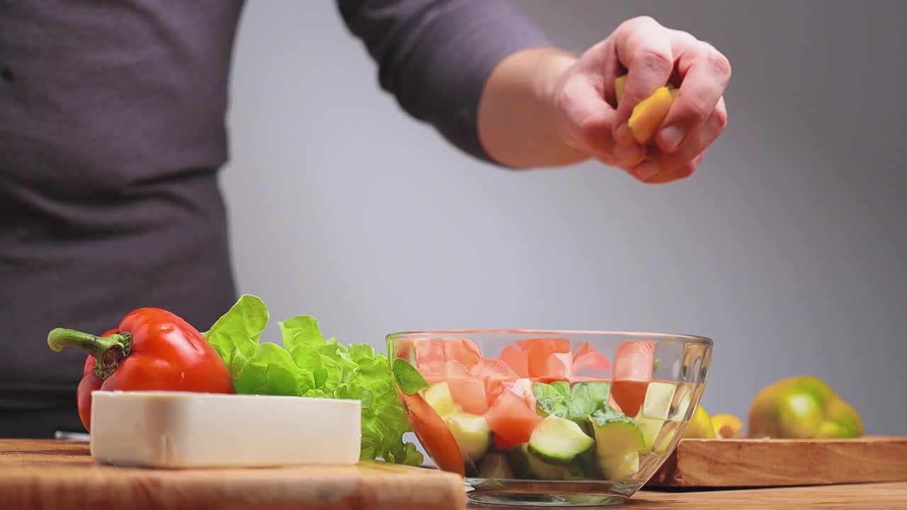 用手将切碎的新鲜甜椒倒入碗中，烹制希腊沙拉、素食视频素材