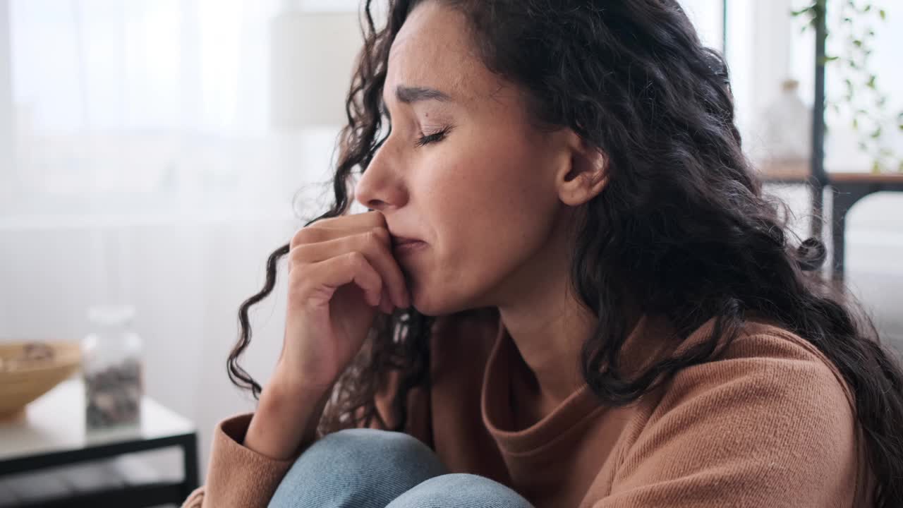 悲伤的女人坐在沙发上哭泣视频素材