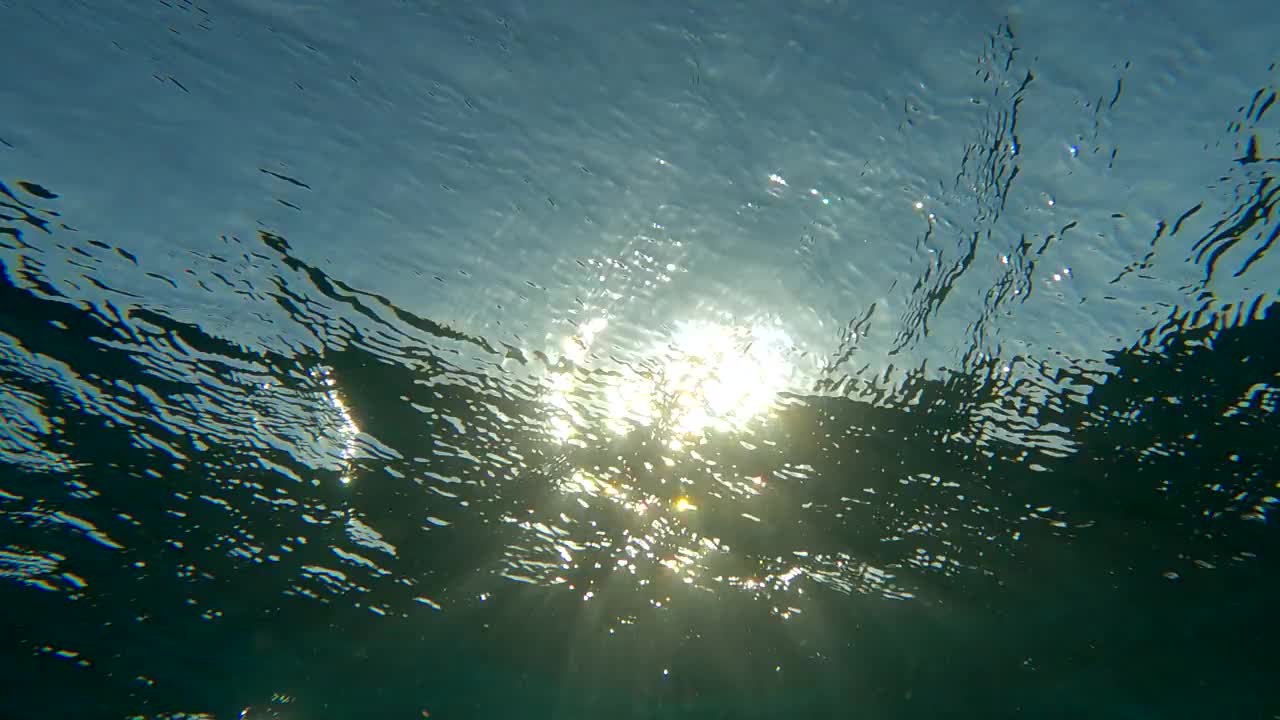 日落时海浪的特写。自然backbround。阳光水下。背光(对景)水下视图。(4 k-60fps)视频素材