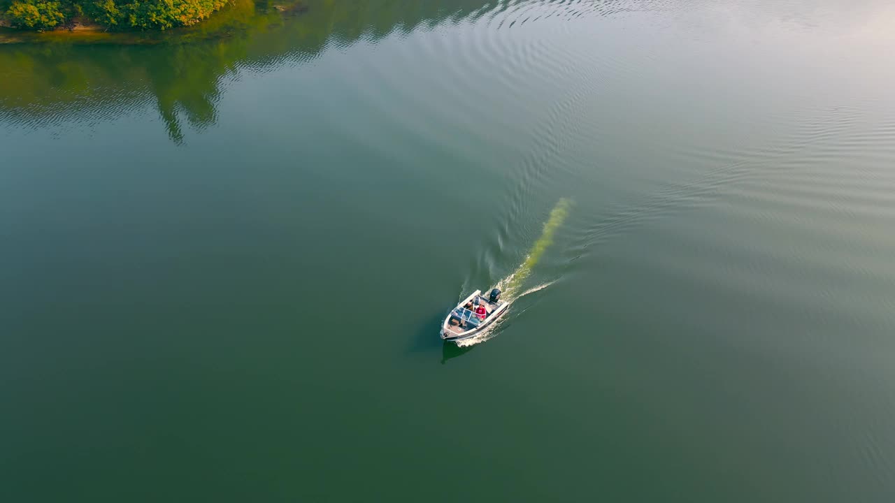 摩托艇和两个人在河上航行。太阳光在水中被反射。在摩托艇上散步。钓鱼快艇视频素材