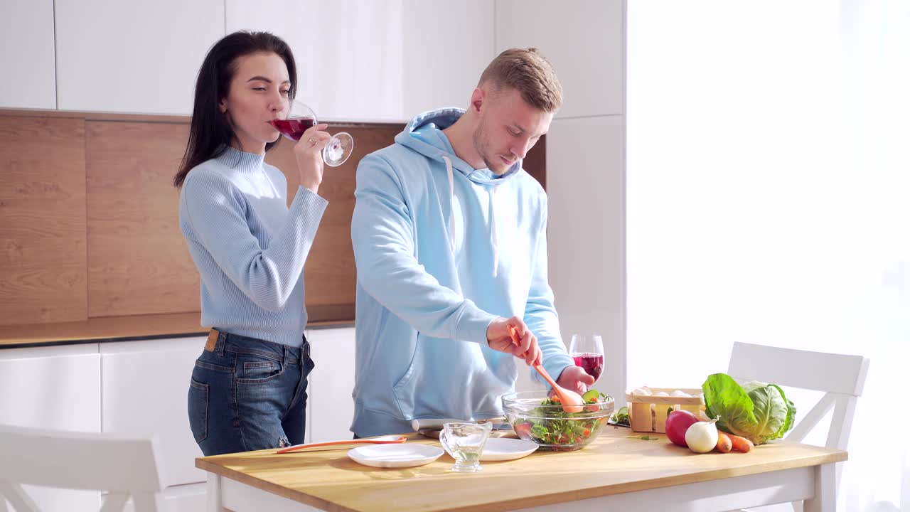 一对相亲相爱的年轻夫妇，在家里的现代厨房里一起烹饪健康的食物。视频素材