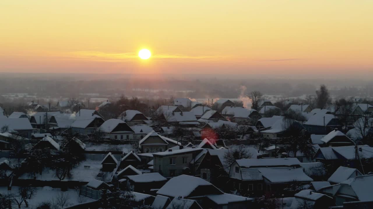 橙色的日出在一个霜冻的冬日早晨，以村庄为背景。美丽的天空和雪花视频素材