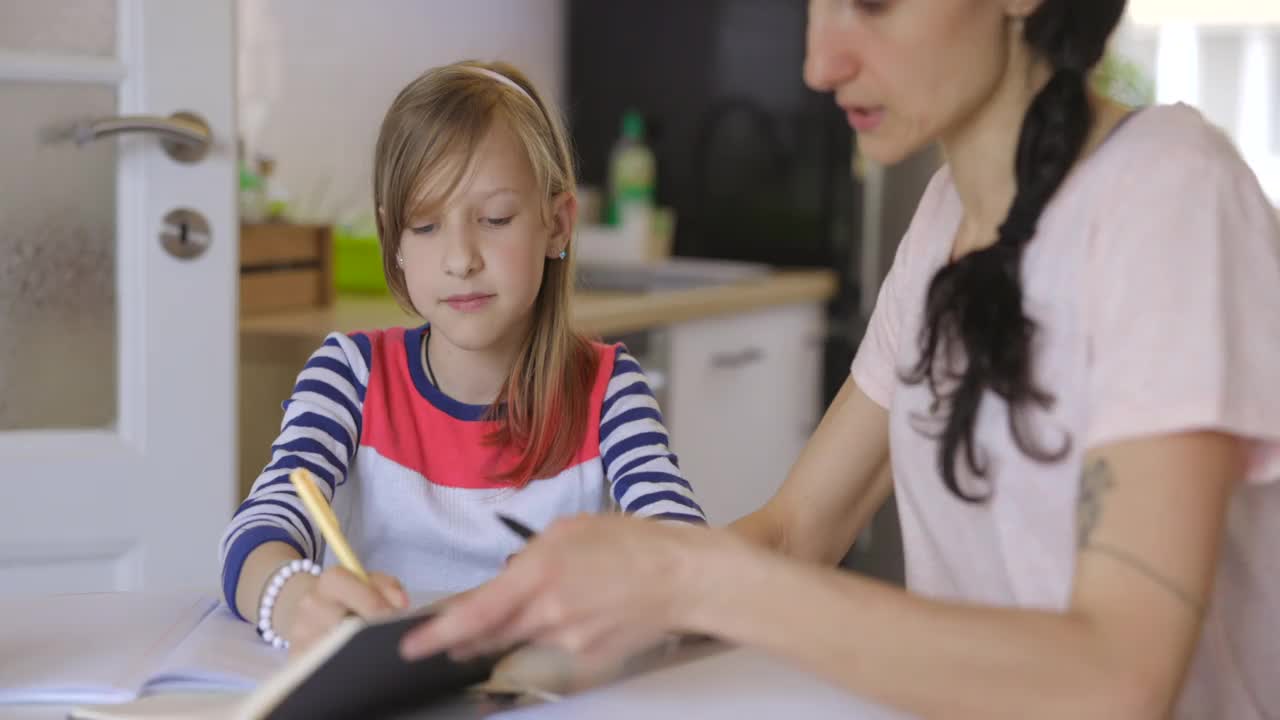 母亲在指导小学女孩做家庭作业视频素材