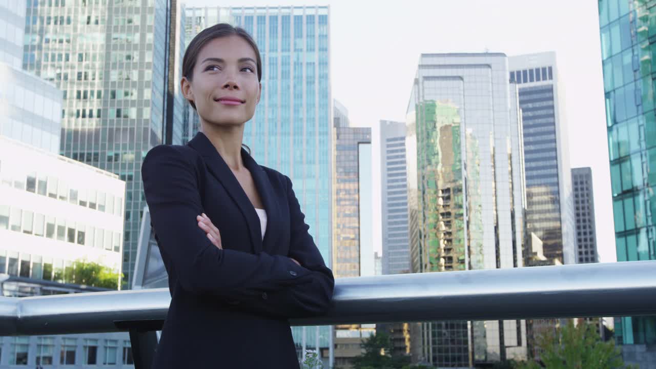 年轻的都市女性职业女商人肖像，西装革履，双臂交叉，站在办公楼外。自信成功的多元文化华人亚裔/白种人女性。视频素材