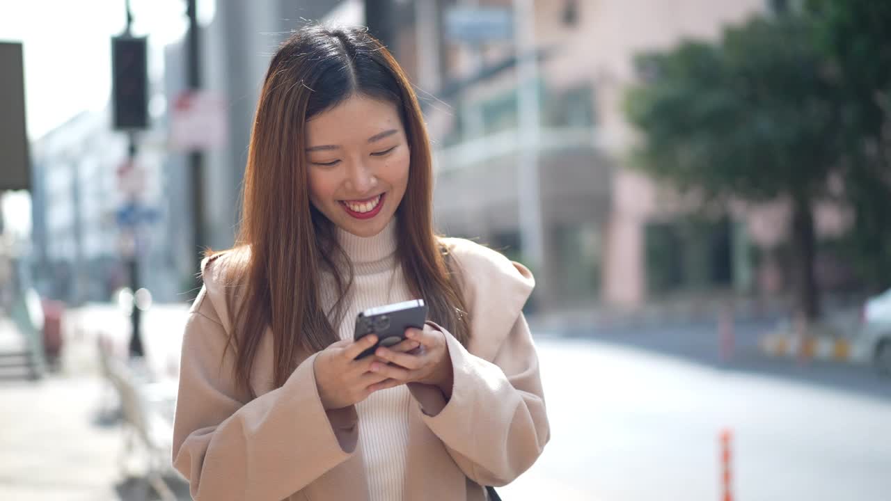 亚洲妇女在城市使用智能手机视频素材