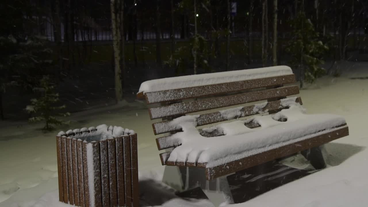 冬夜在公园的长凳上，在一盏灯笼的灯光下，雪花正在飘落视频素材