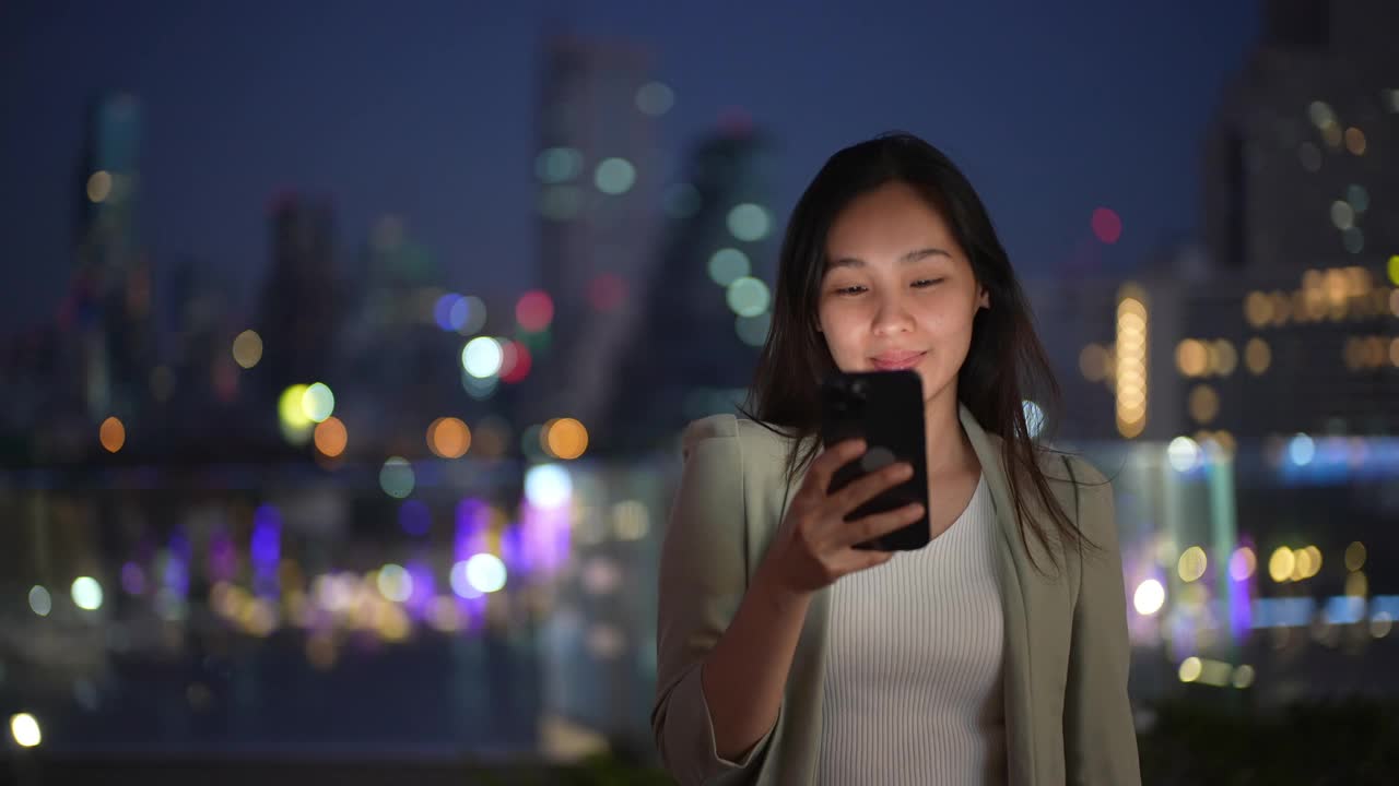 女商人晚上在城市里使用智能手机视频素材