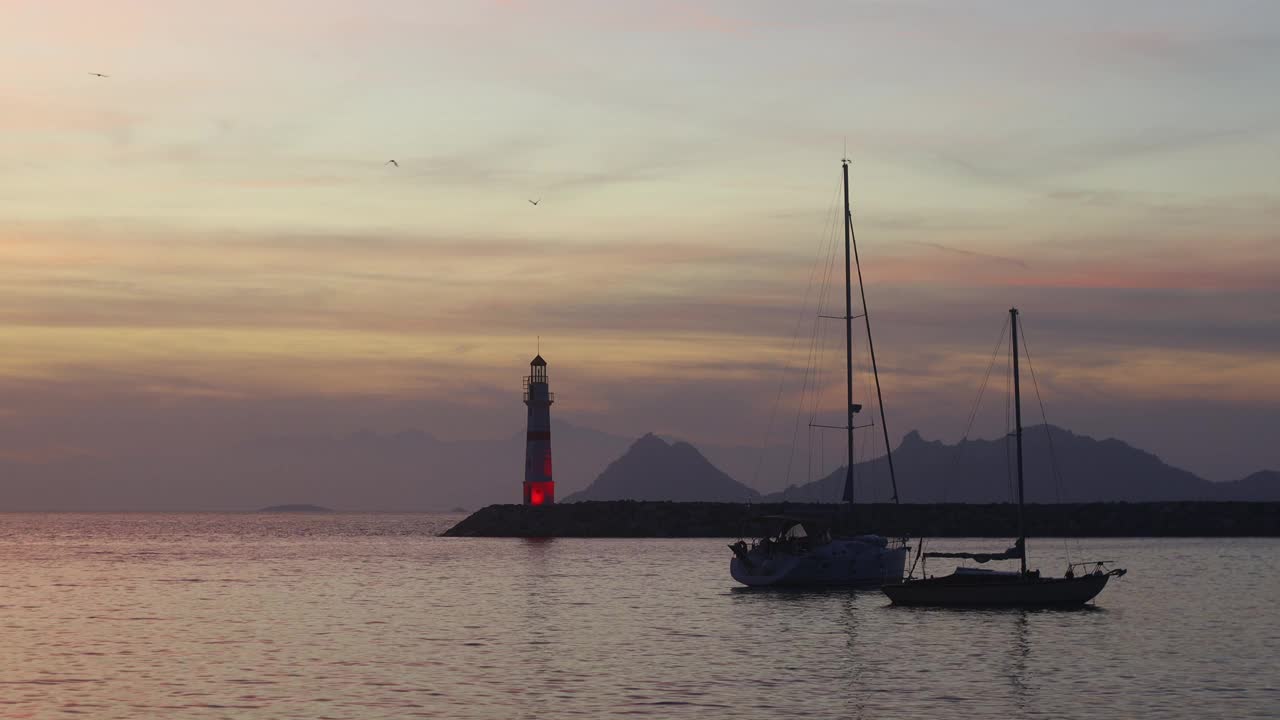 在夕阳海景。海岸上的灯塔。海边小镇Turgutreis和壮观的日落视频素材