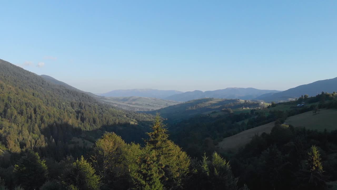 一列火车的鸟瞰图，火车离开隧道，在夏季的山上郁郁葱葱的绿色森林。视频下载