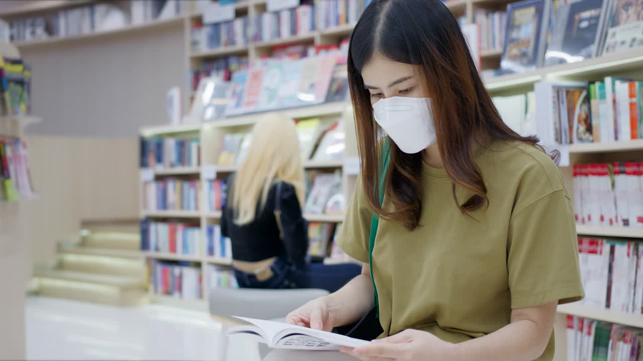 一个亚洲女人在图书馆找书视频素材