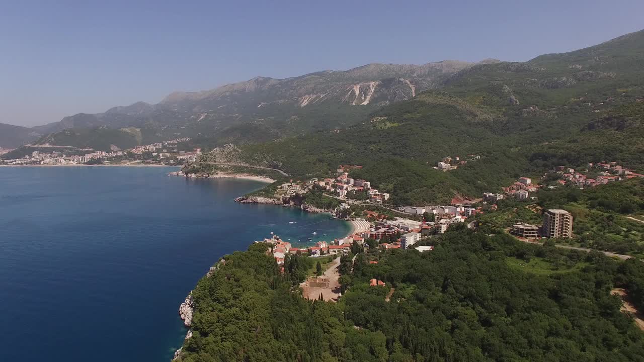 海边的建筑被绿树和群山环绕。无人机视频素材