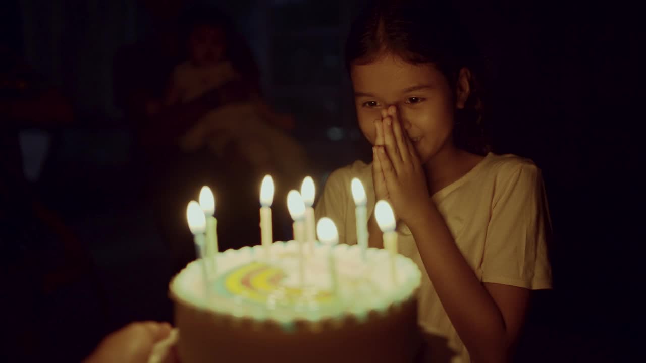 小女孩喜欢在家里吹生日蛋糕上的蜡烛。视频素材