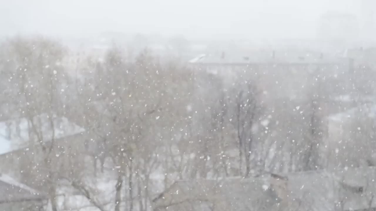 失去焦点的城市背景与雪花飘落。视频素材