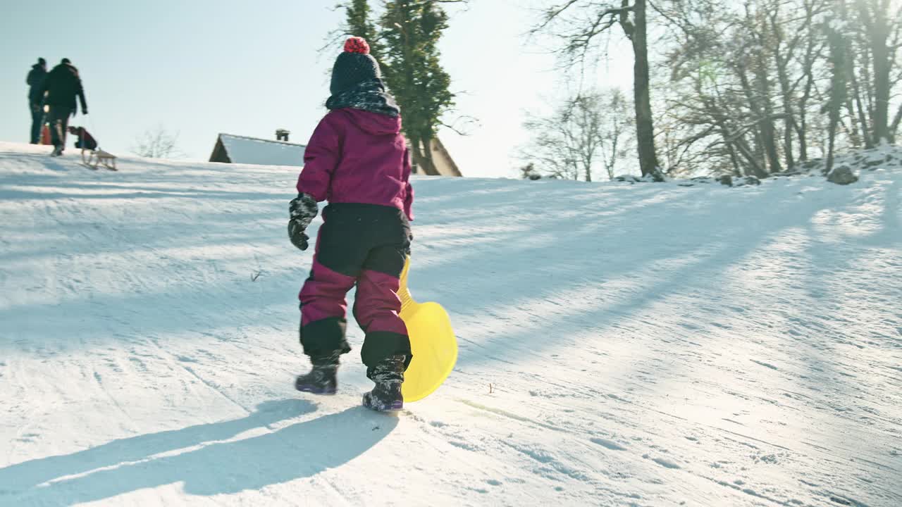 孩子沿着雪橇滑道上坡视频素材