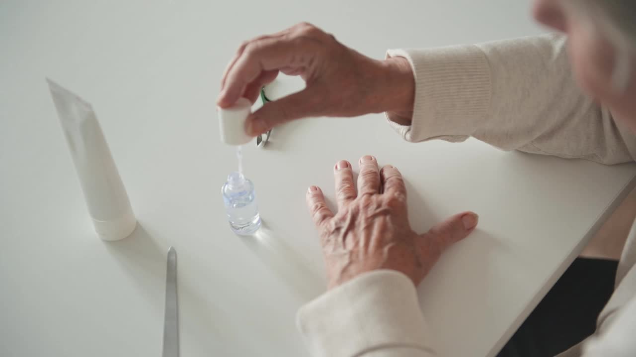 有皱纹的年长女性在指甲上涂透明指甲油视频下载