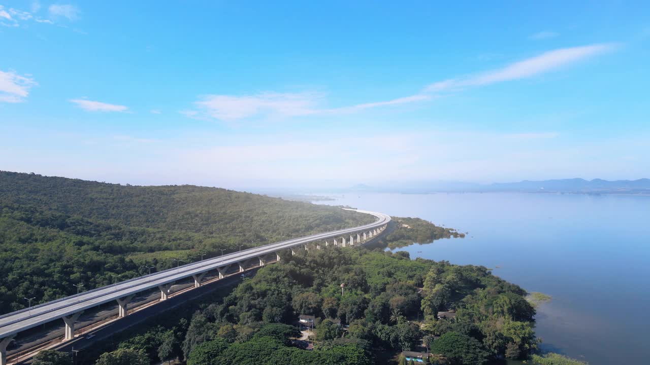 空中无人机超延时延时美丽的高速公路在绿色森林与大坝在公路的一边之间的山。视频下载