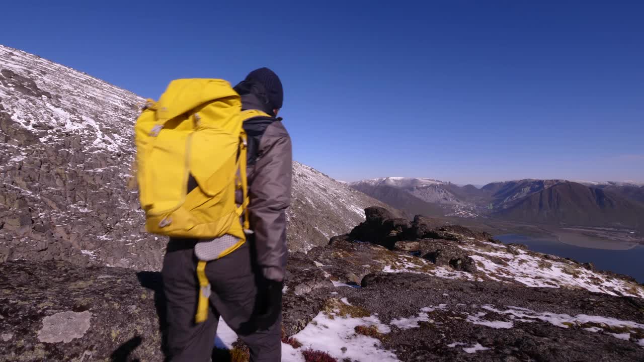 在山里背着背包的旅游者。秋日的希比尼山。美丽的山景。阳光下积雪覆盖的山峰视频素材