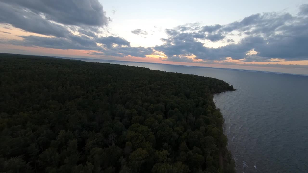 这是美国密歇根州苏必利尔湖日落时，风和海浪袭击一个半岛海岸线的鸟瞰图视频素材