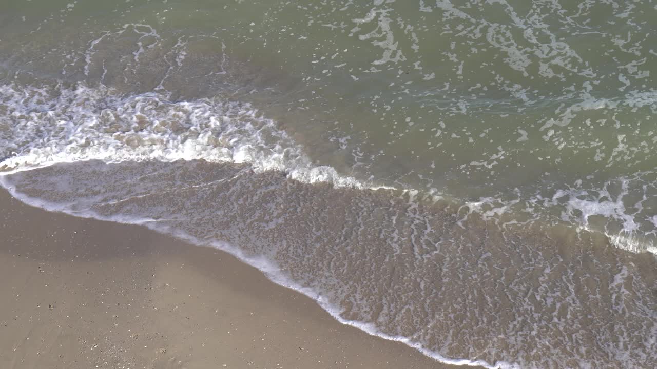 俯视沙滩，海浪拍打着海岸，海水泡沫四溅。美丽舒缓的视频，放松。海洋景观，风暴黑海。大海里的水又脏又浑。视频素材