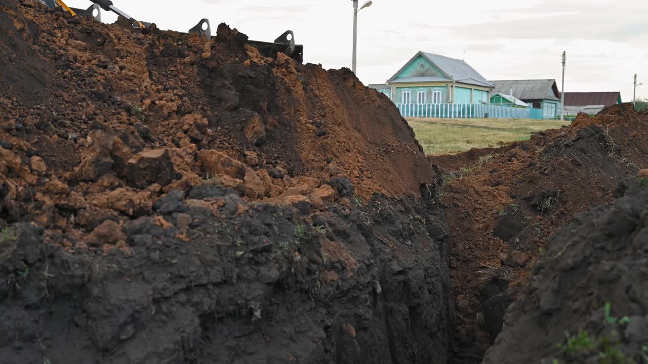 土方工程在农村。现代推土机在建筑工地掩埋壕沟视频下载