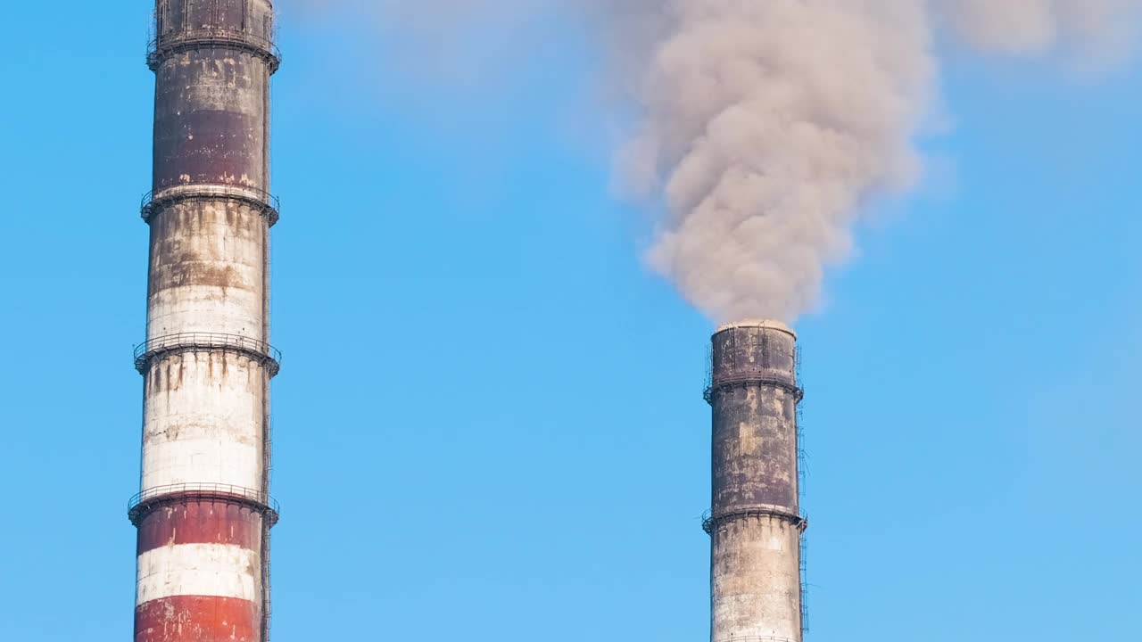 特写镜头:火力发电厂的高管道，黑烟向上移动，污染大气。用化石燃料概念生产电能视频素材