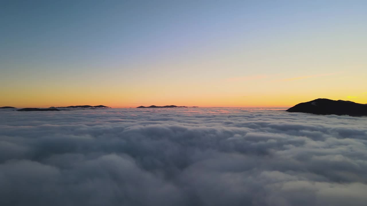 鸟瞰图的生机勃勃的日出在白色浓密的云与遥远的黑暗的山脉在地平线上视频素材