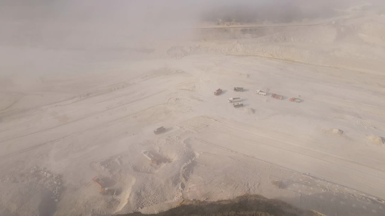 用挖掘机和自卸卡车对建筑工业用石灰石露天开采的鸟瞰图视频素材