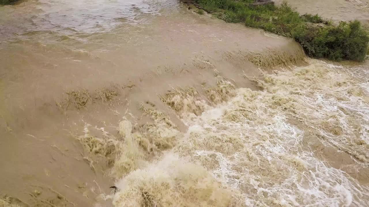 鸟瞰图宽阔的肮脏的河流与泥泞的水在洪水期间在暴雨的春天。视频素材