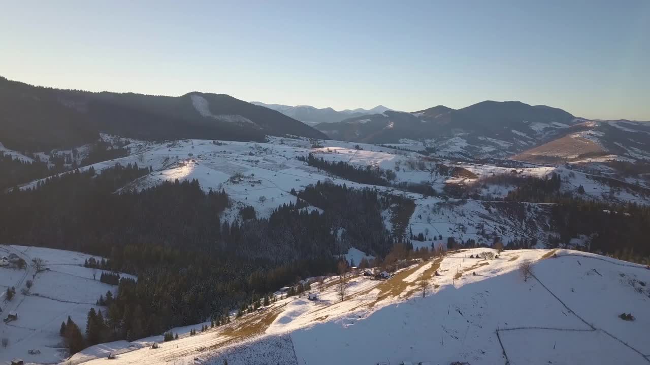 鸟瞰图小村庄与散落的房屋在冬季积雪覆盖的小山和裸露的喀尔巴阡山脉在乌克兰。视频素材