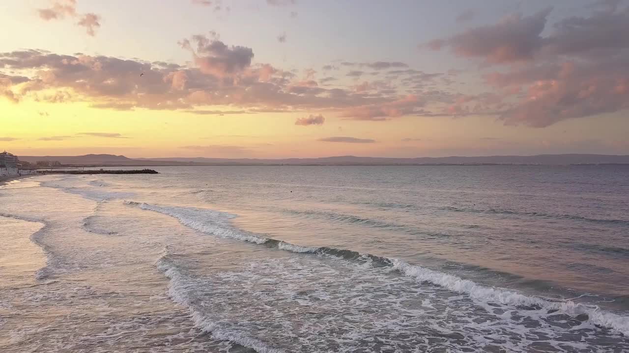 两把红色遮阳伞，在夕阳的海浪中撑在沙滩上。视频素材