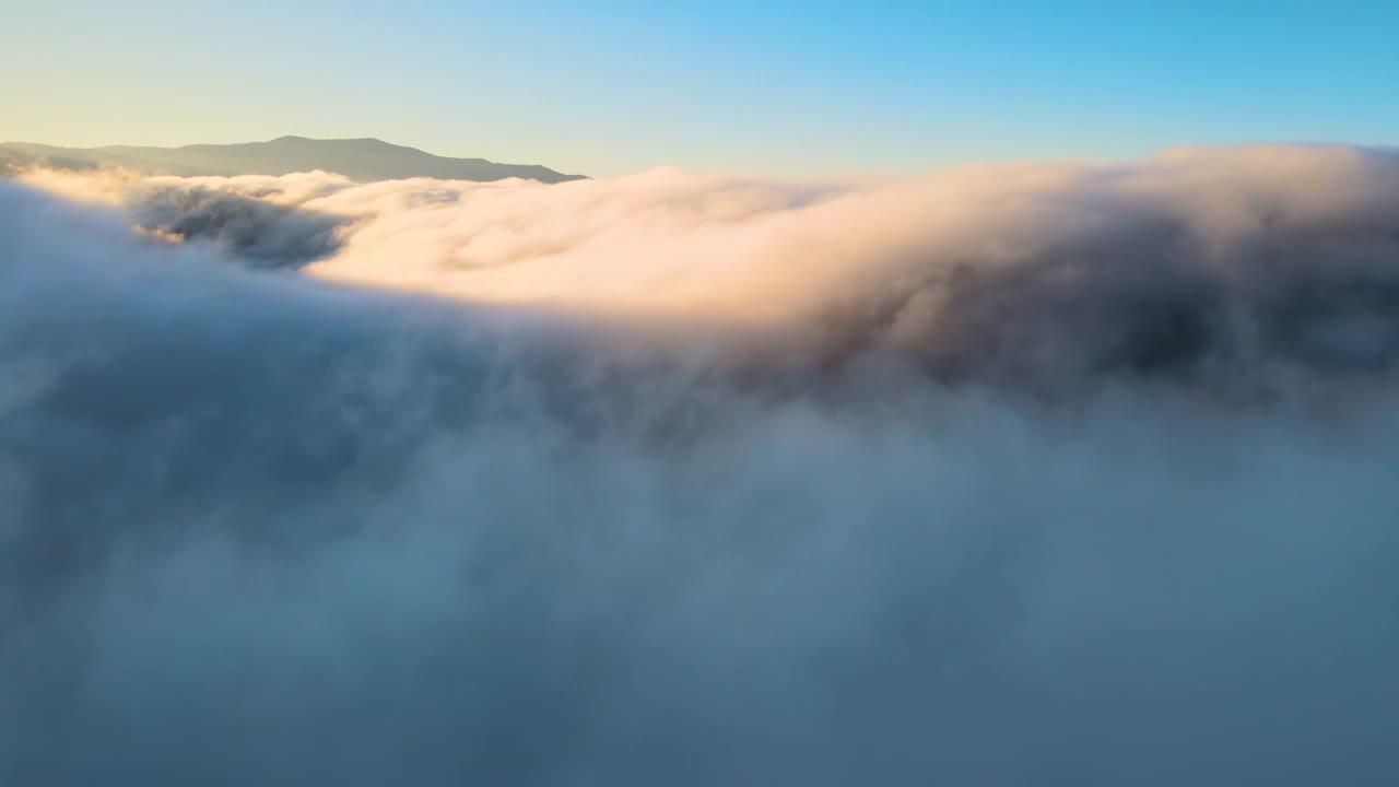 鸟瞰图的景观在雾蒙蒙的快速移动的云覆盖山在日落视频素材