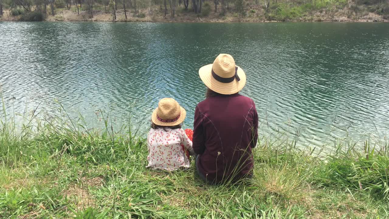 母女俩坐在湖岸上看着淡水视频素材