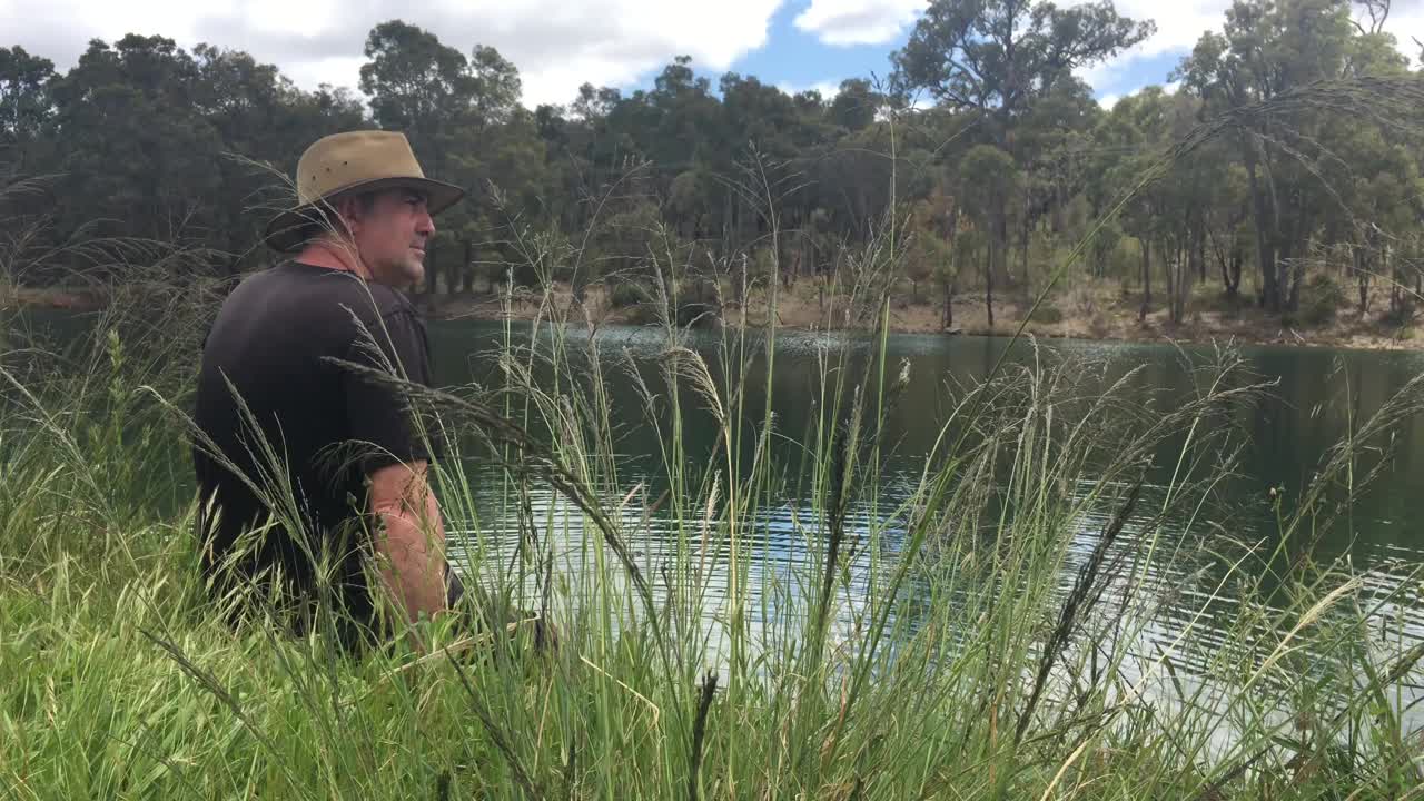 成年男子坐在湖岸上视频素材