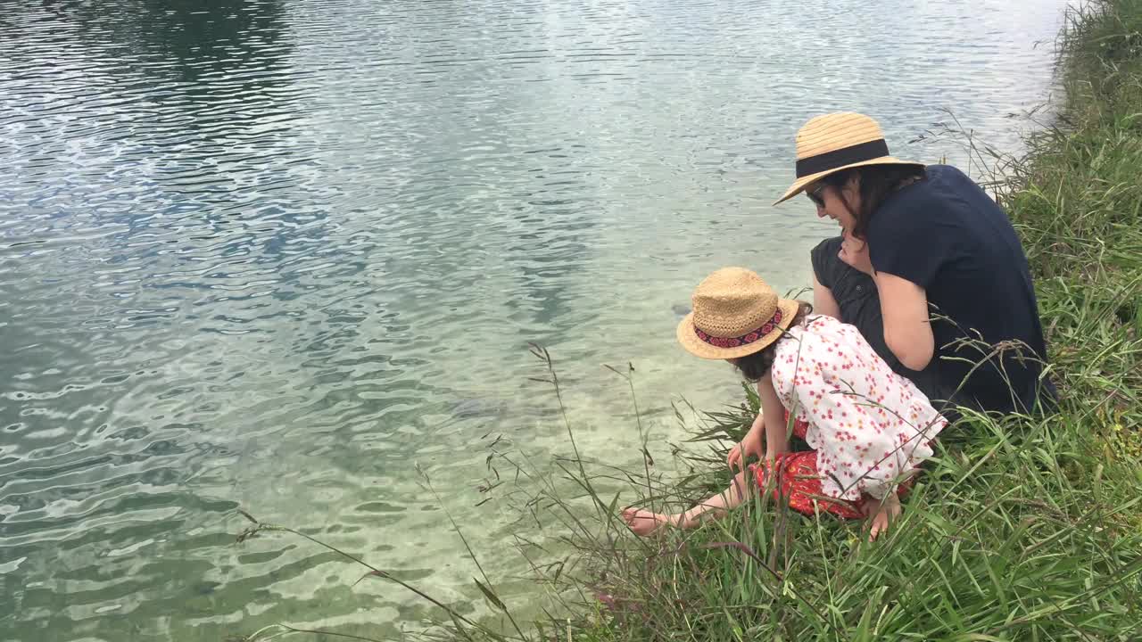 母女俩坐在湖岸上看着淡水视频素材