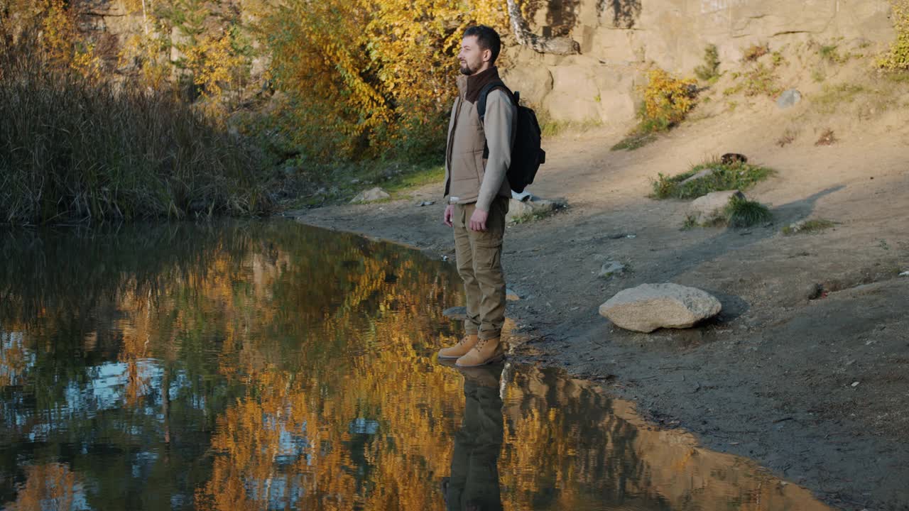 一名背着背包的男性游客，站在湖边欣赏大自然视频素材