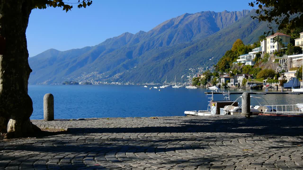 在阳光明媚的日子里，一个男人看着一个空的秋千和山在海滨视频素材