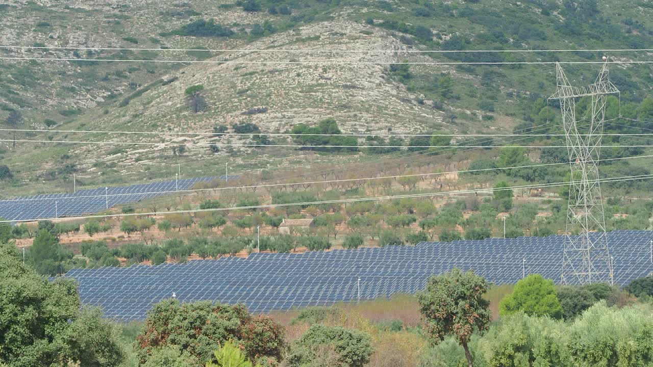 田间的太阳能电池板带有高压电塔。视频素材