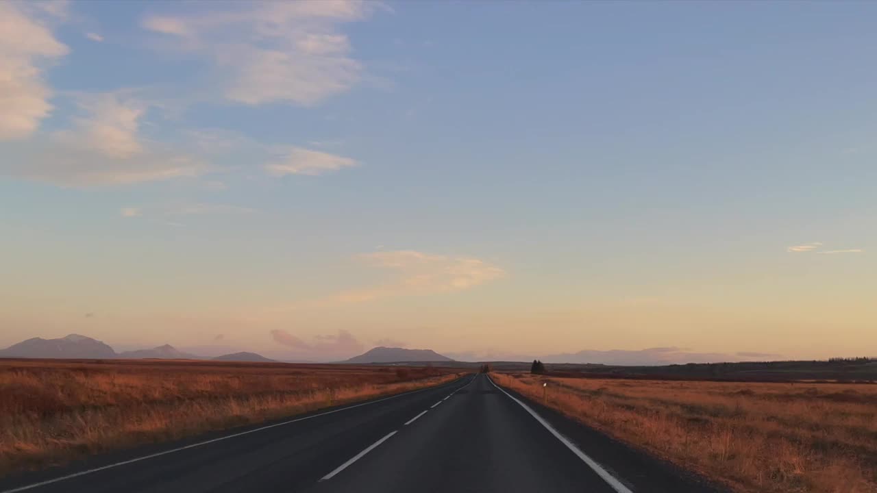 在美丽的晨光中行驶在冰岛笔直的道路上。视频素材