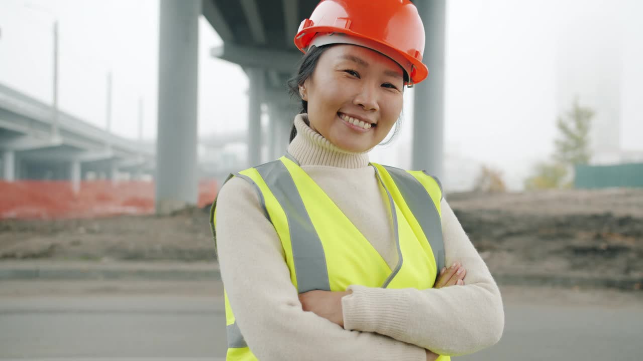 亚洲女性建筑工人的肖像，戴着安全帽和背心在户外微笑视频素材